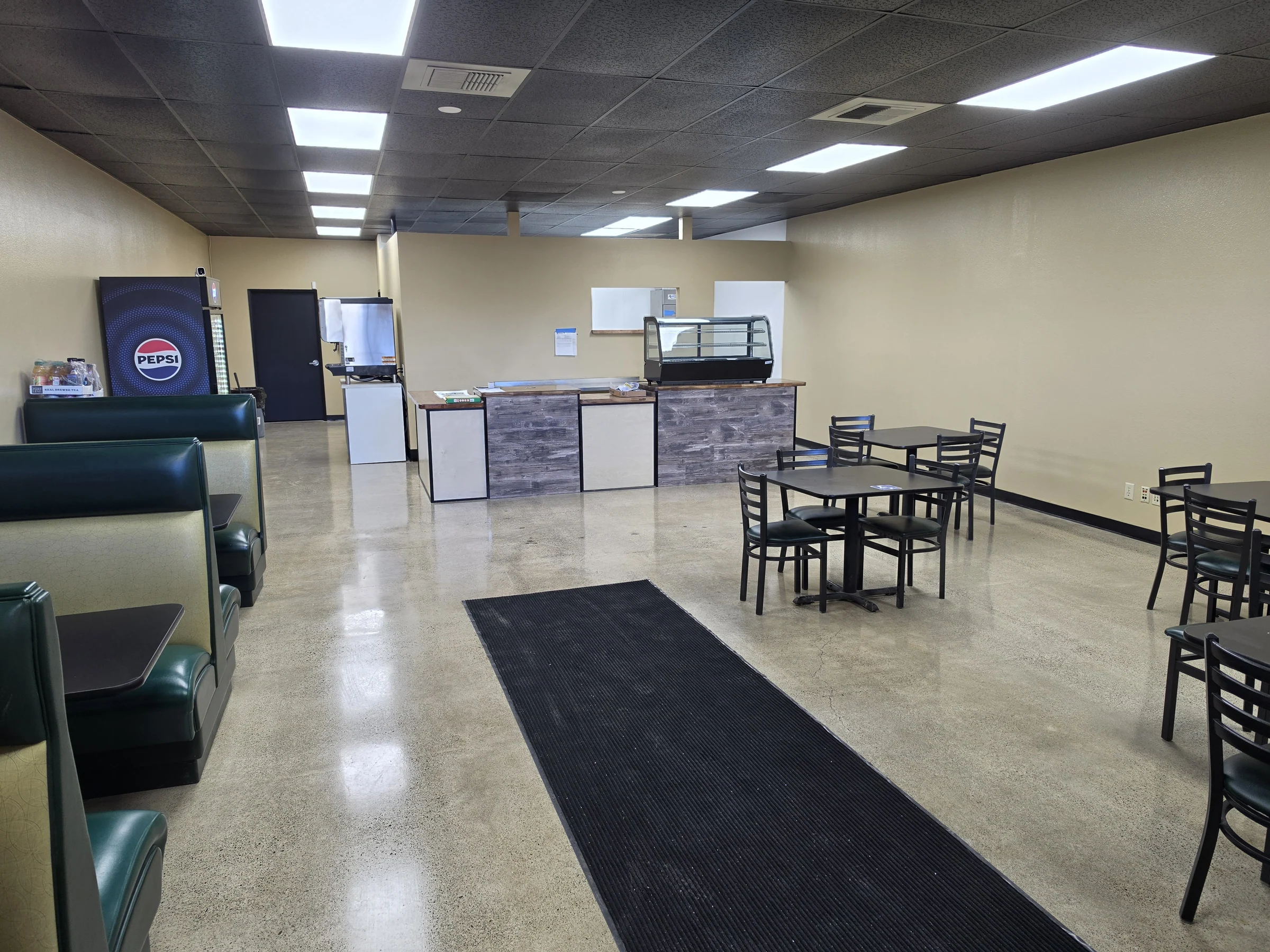 View across restaurant seating toward the Benji’s Deli service counter and display case.