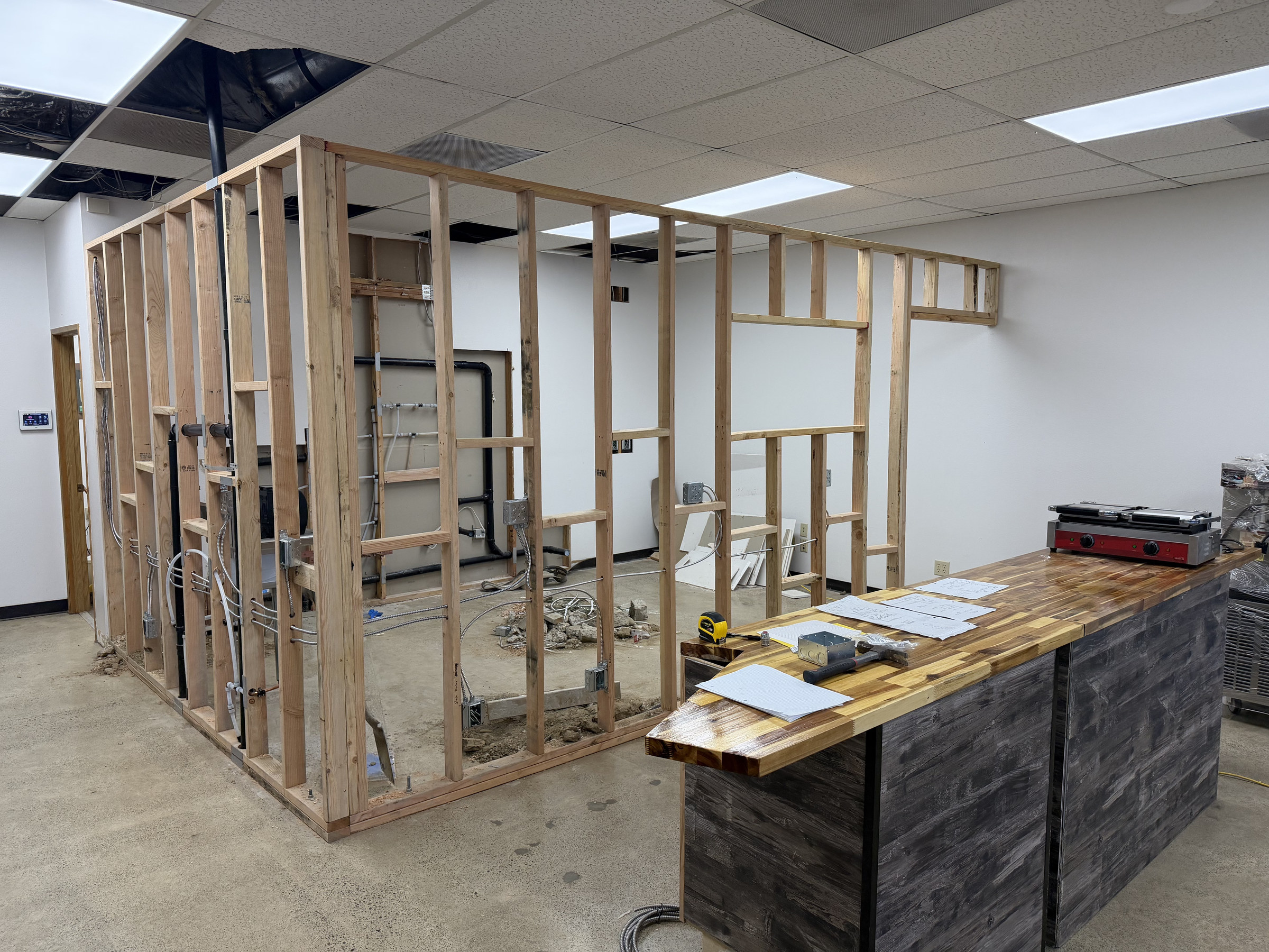 Wide view of the restaurant build-out with interior wall framing and a service counter taking shape.