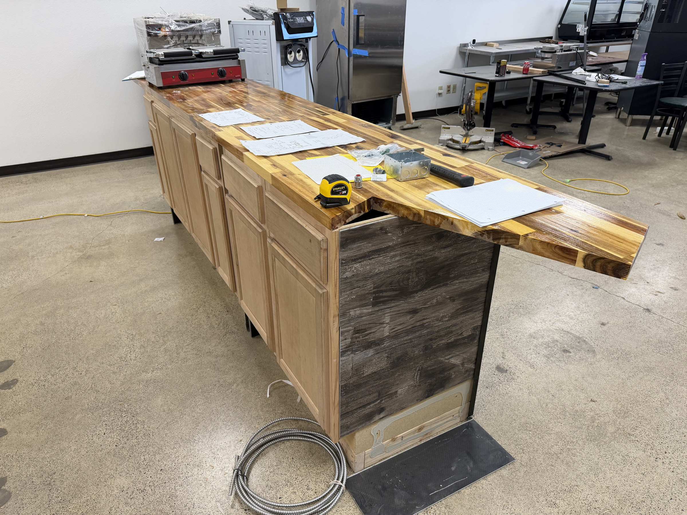 Close-up of the wood-top customer service counter and cabinet base during the build-out.