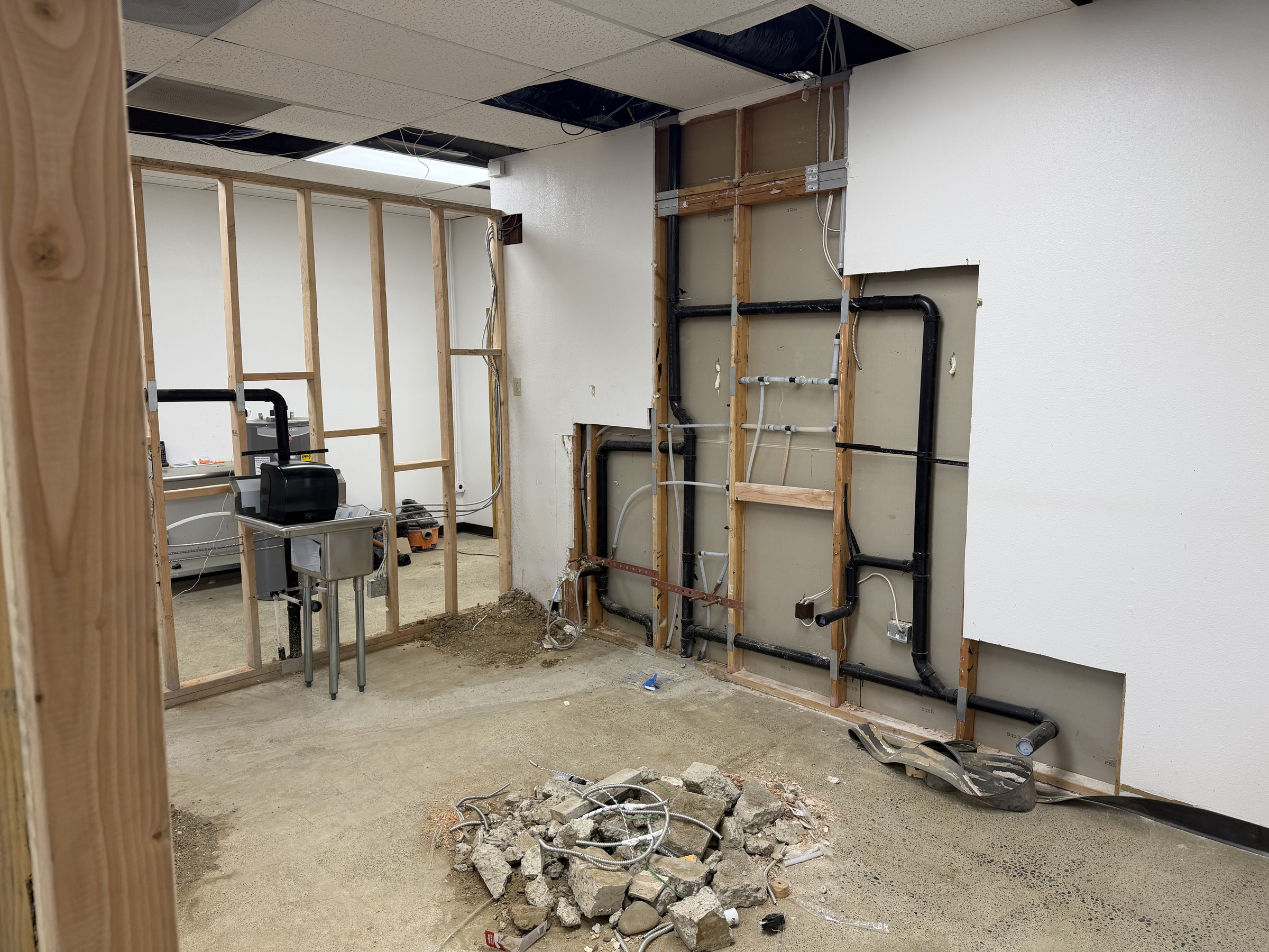 Exposed piping and wall framing during the tenant-improvement construction phase.