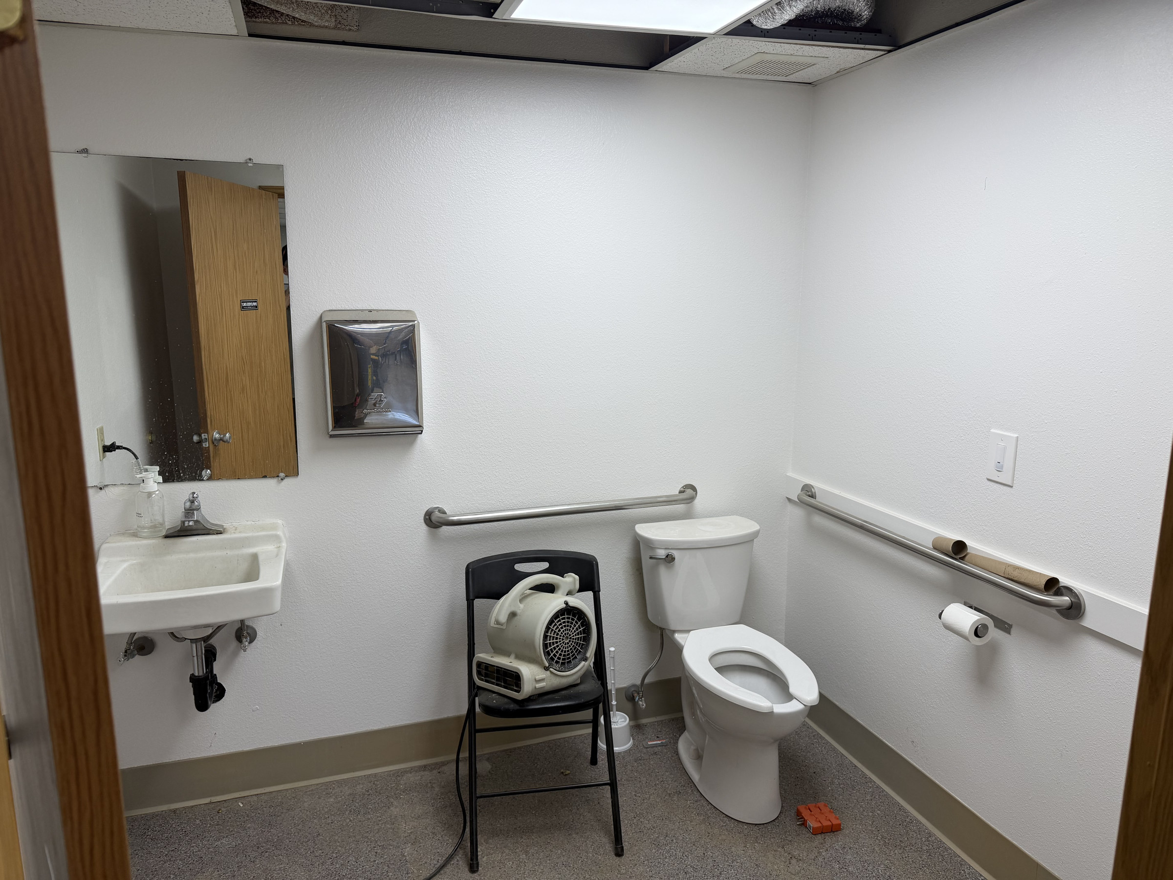 Restroom area pictured during construction with accessible fixtures and grab bars visible.